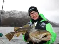 Glad fiskare visar upp en stor torsk fångad i Norge.