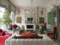 Maximalism inredning med blommig tapet, kristallkrona, röda och grå möbler samt konstverk.