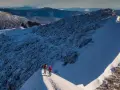 Två vandrare på en snöig bergskam, redo att bestiga Kebnekaise. Vacker utsikt över fjällen.
