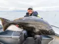 Lycklig fiskare med en enorm hälleflundra, ett bevis på framgångsrikt havsfiske i Norge.