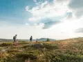 Familj vandrar i solnedgången vid Beitostølen sommar. Barnen springer glatt före föräldrarna genom det kuperade landskapet.