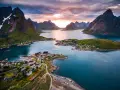 En pittoresk by med röda hus vid en fjord, omgiven av dramatiska berg. En av de fina platserna i Norge, badande i solnedgångens ljus.