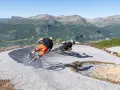 Två cyklister kör utför en grusig bana i Hemsedal sommar. Berg och grönska i bakgrunden.