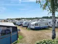 En stor campingplats med många husvagnar. Solen skiner och himlen är blå.