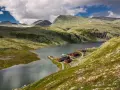 En vacker vy över en sjö med röda stugor vid en fjällsluttning, perfekt för en triangeltur i Norge.