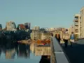 Promenad över bron i Oslo centrum med moderna byggnader och vatten.