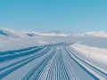Perfekt preparerade spår för längdskidåkning i Hemsedal. Solen lyser på de snötäckta bergen och den blå himlen.
