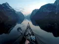 Kajakpaddling i en norsk fjord med snöklädda berg som speglar sig i det lugna vattnet. En fantastisk utsikt över son Norge.