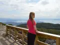 Kvinna i rosa tröja njuter av utsikten över ett storslaget Norge med fjäll och fjordar.