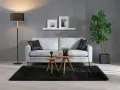 En modern soffgrupp med soffa, soffbord och golvlampa. De organiska formerna i soffbordet och krukan ger en mjuk känsla.