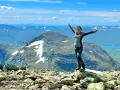 Lycklig vandrare på en bergstopp med vidsträckt utsikt över fjällandskap. Här finns fina vandringsleder för alla.