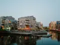 Moderna byggnader längs en kanal i Oslo. Folk sitter på trappor vid vattnet. Besök Oslo för en härlig kväll.