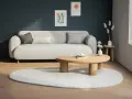 En ljus soffa med kuddar, ett runt träbord och en rund matta. En vas med torkade blommor på en pall. Olika inredningsstilar kan inspirera detta lugna rum.