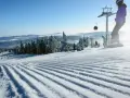 Perfekt preparerad pist för sommarskidåkning i Norge. En snowboardåkare och en skidåkare njuter av den soliga dagen.