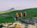 Tre vänner vandrar på en stig i fjällen, redo för äventyr med sina ryggsäckar. En perfekt stund för att kolla stf packlista.