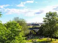 En solig dag med en härlig piknik i parken. Människor njuter av gräset och utsikten över staden.