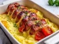 En härlig ugnsbakad falukorv med krämigt potatismos och rostade tomater, toppad med färsk persilja. En klassisk svensk rätt som värmer själen.