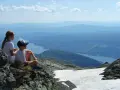 Två barn vilar på en klippa med utsikt över en sjö och berg. Perfekt för vandringsleder i Åre.