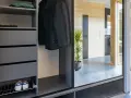 Snygga inredningstips hall: mörk garderob med rockar, mössor, skor och en grön växt som speglas i en stor glasdörr.