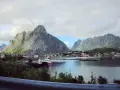 Vacker vy över en by vid vattnet, omgiven av dramatiska berg. Kanske en vy från Narvik mot Lofoten?