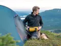 Man med hund packar för vandring. En gul sovsäck ligger redo. Perfekt packlista vandring dagstur.