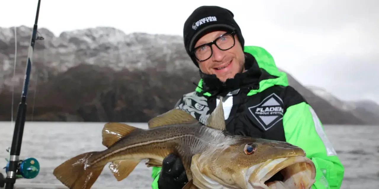 Glad fiskare visar upp en stor torsk fångad i Norge.