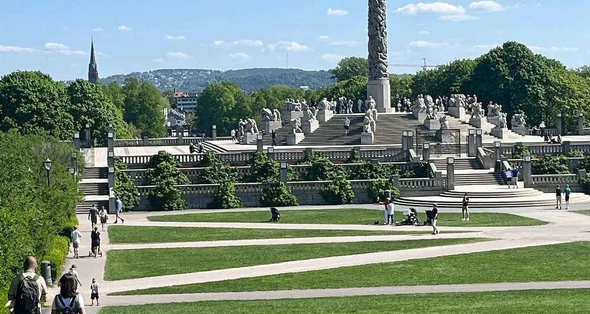 Vigelandsparken med dess imponerande monoliten och skulpturer, en solig dag med besökare som njuter av parken.