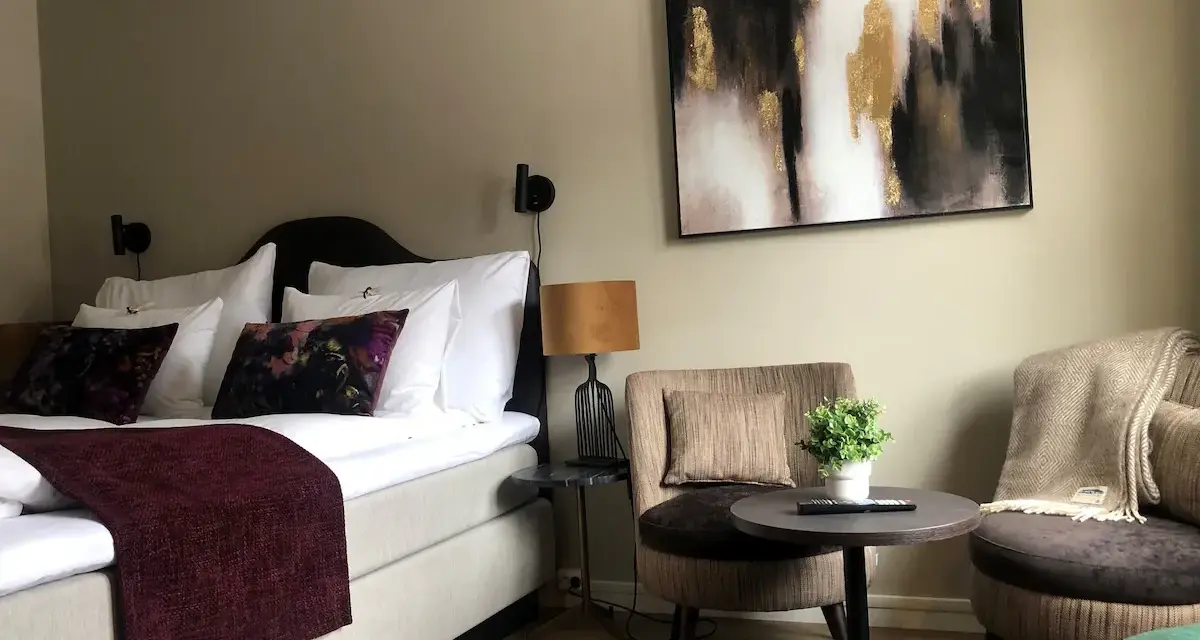 Mysigt hotellrum inredning med stor säng, bekväma fåtöljer och modern konst.