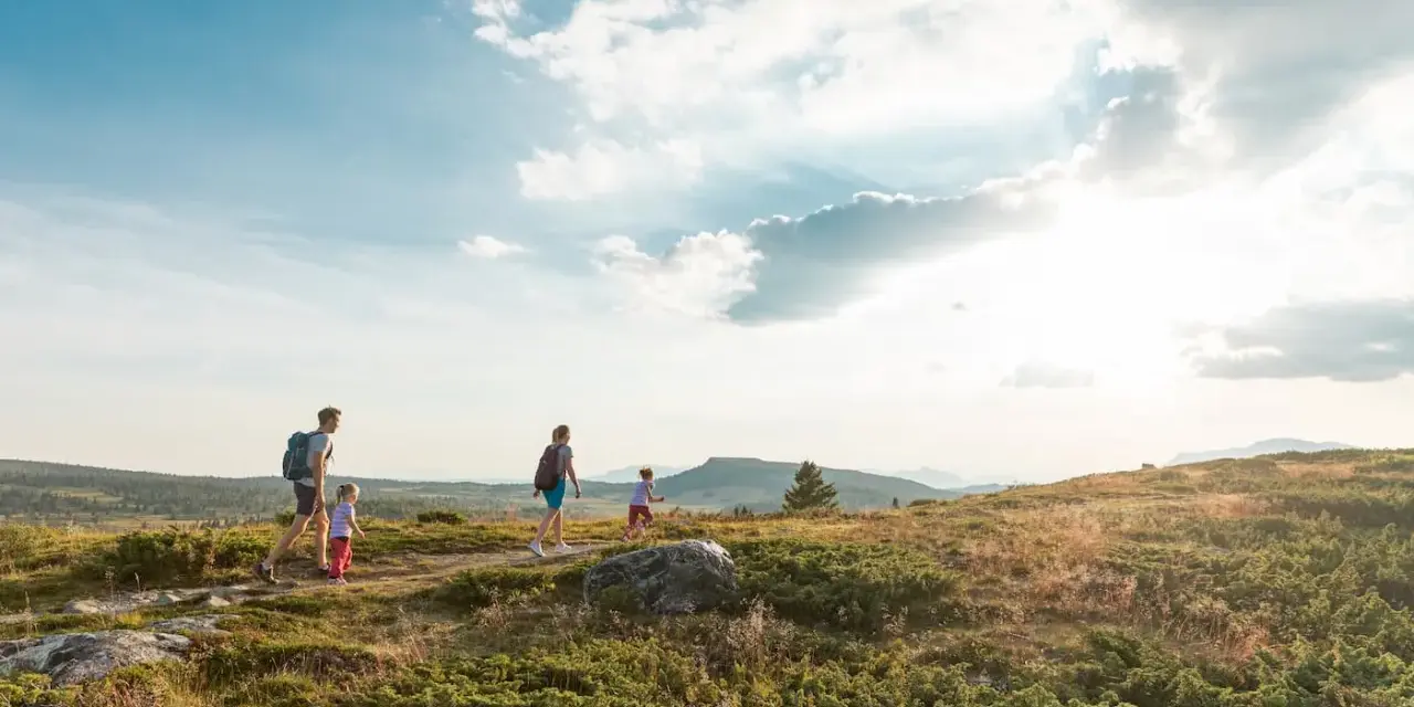 Familj vandrar i solnedgången vid Beitostølen sommar. Barnen springer glatt före föräldrarna genom det kuperade landskapet.