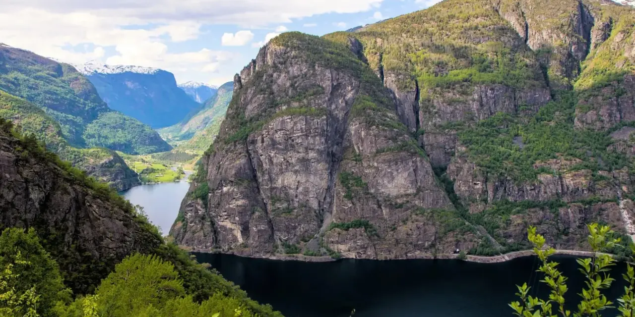 Majestätiska bergsklippor reser sig över en mörk fjord, en vy som lockar till en oförglömlig **aurlandsdalen vandring**.