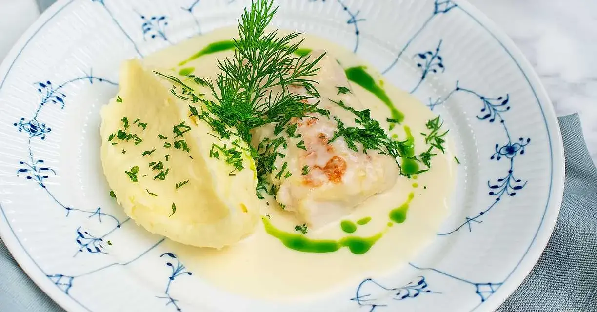 En vacker tallrik med torsk i en krämig sås, serverad med potatismos och dill. Ett perfekt torsk recept för en festmåltid.