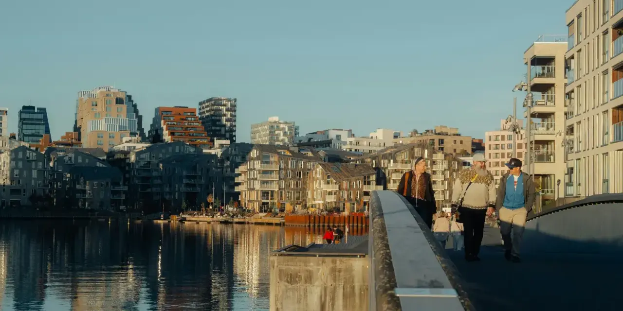 Promenad över bron i Oslo centrum med moderna byggnader och vatten.