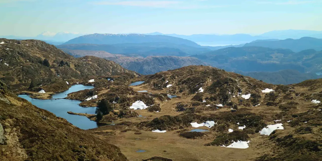 Vacker utsikt över Ulriken i Bergen med små sjöar och snöfläckar på bergssluttningarna.
