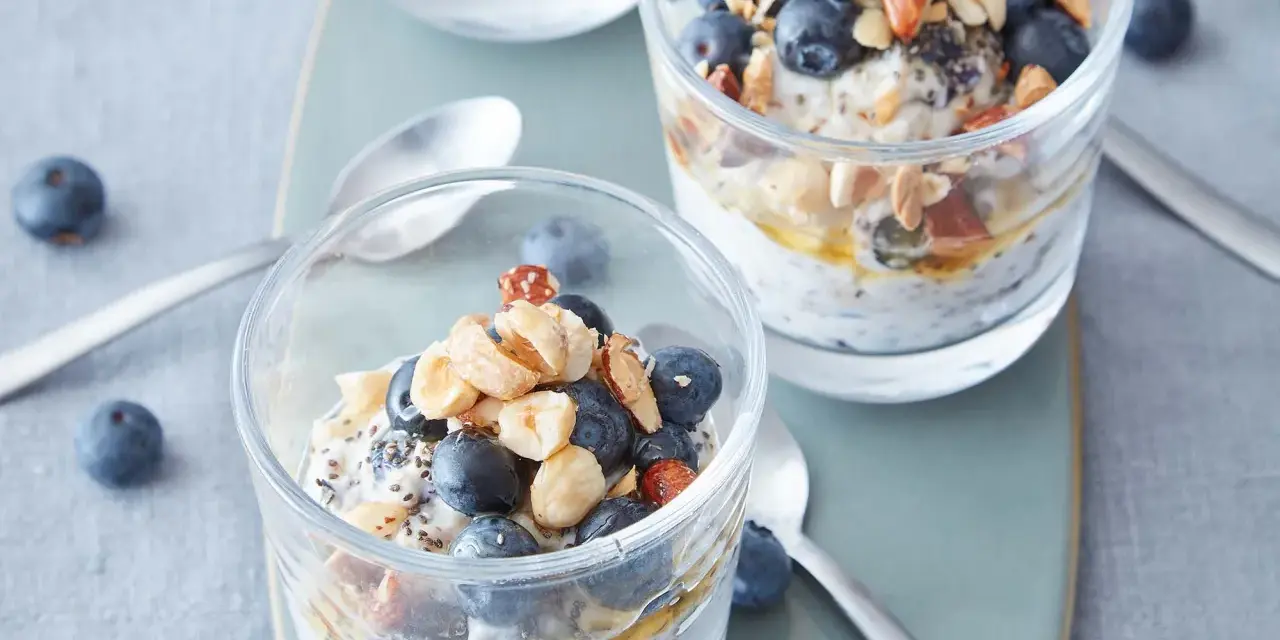 Två glas med overnight oats, toppade med blåbär, nötter och honung. Perfekt frukost!