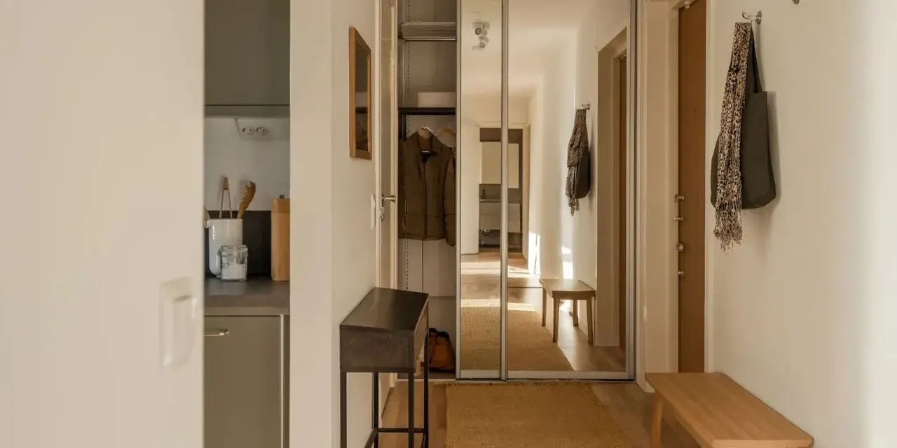 Liten hall inspiration med skjutdörrsgarderob i spegelglas, en smal konsol och en bänk i trä.