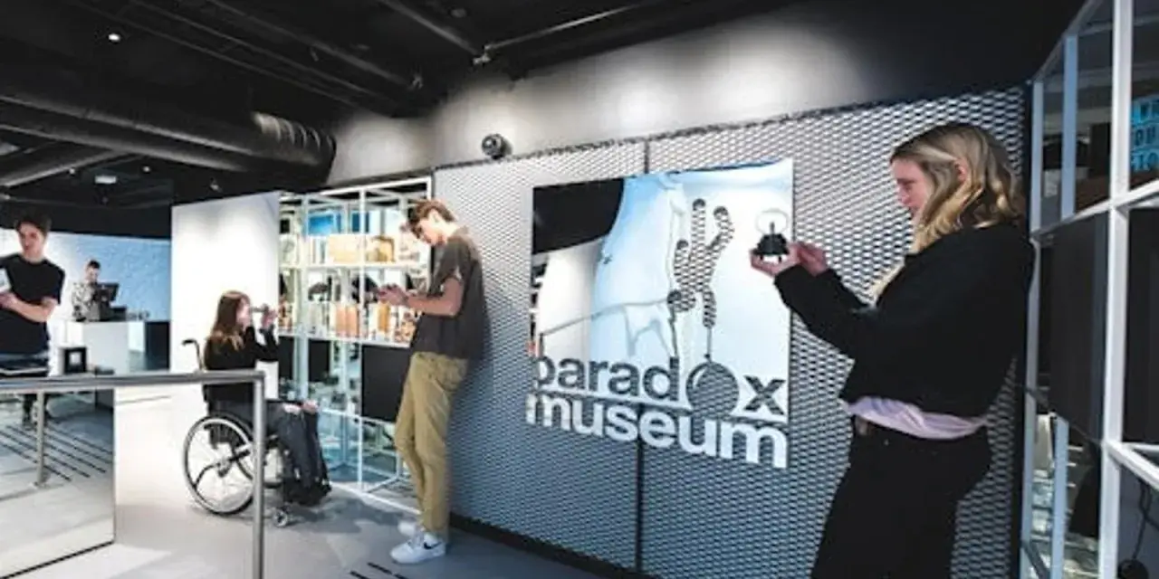 Besökare utforskar utställningar på Paradox Museum Oslo. En kvinna i rullstol tittar på sin telefon.