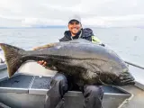 Lycklig fiskare med en enorm hälleflundra, ett bevis på framgångsrikt havsfiske i Norge.