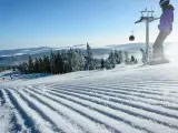 Perfekt preparerad pist för sommarskidåkning i Norge. En snowboardåkare och en skidåkare njuter av den soliga dagen.
