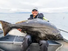 Lycklig fiskare med en enorm hälleflundra, ett bevis på framgångsrikt havsfiske i Norge.