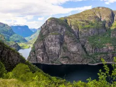 Majestätiska bergsklippor reser sig över en mörk fjord, en vy som lockar till en oförglömlig **aurlandsdalen vandring**.