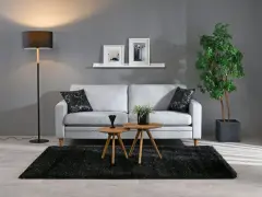 En modern soffgrupp med soffa, soffbord och golvlampa. De organiska formerna i soffbordet och krukan ger en mjuk känsla.