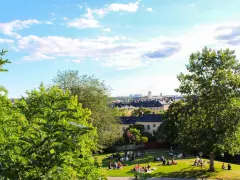 En solig dag med en härlig piknik i parken. Människor njuter av gräset och utsikten över staden.