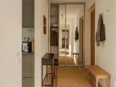 Liten hall inspiration med skjutdörrsgarderob i spegelglas, en smal konsol och en bänk i trä.