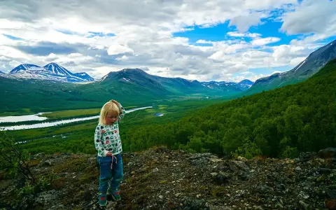 Ett barn funderar på den storslagna utsikten under en vandring med barn i fjällen.
