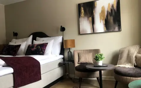 Mysigt hotellrum inredning med stor säng, bekväma fåtöljer och modern konst.