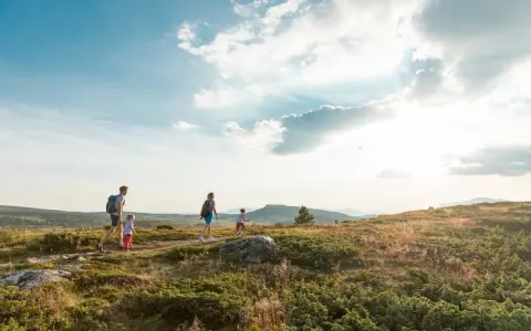 Familj vandrar i solnedgången vid Beitostølen sommar. Barnen springer glatt före föräldrarna genom det kuperade landskapet.