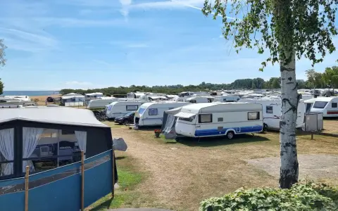 En stor campingplats med många husvagnar. Solen skiner och himlen är blå.