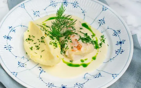 En vacker tallrik med torsk i en krämig sås, serverad med potatismos och dill. Ett perfekt torsk recept för en festmåltid.
