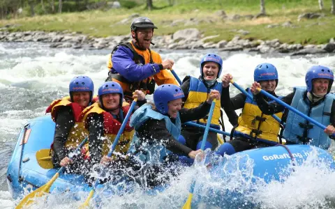 Glada människor i en flotte på forsigtigt vatten, redo för sjoa rafting.