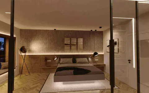 Sovrum med modern belysning. En säng med mörka sängkläder står på en matta. Väggen bakom sängen har en textur och är upplyst av LED-lister. Golvet är parkett.